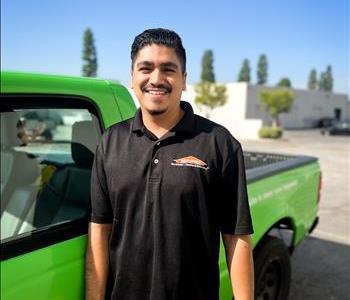 male employee with black shirt in front of green truck